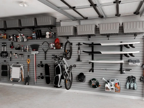 Wall-mounted garage shelving loaded with tubs and tools